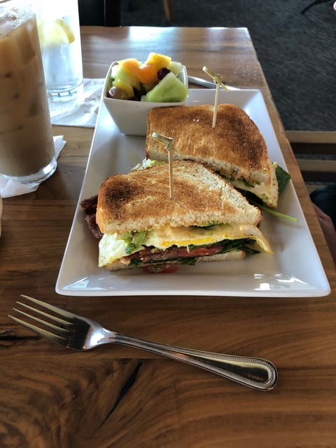 Gourmet Avocado, Egg, and Applewood Bacon Breakfast Sandwich served with Fresh Fruit and Cold Brew Coffee