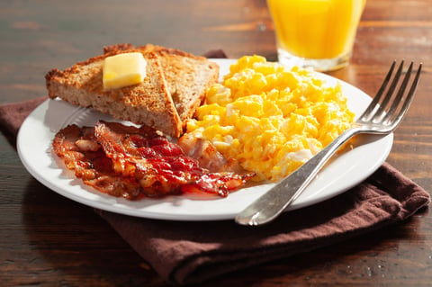 Traditional scrambled egg breakfast with bacon and toast