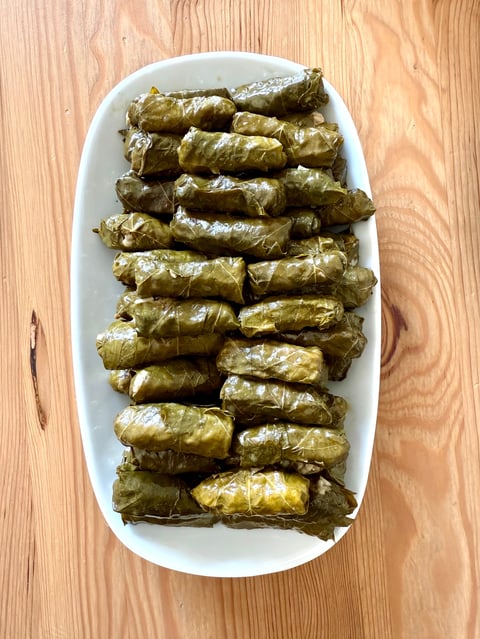 Stuffed leaves with olive oil on a wooden background. Mediterranean cuisine delicacies.