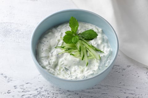 Fresh traditional Greek tzatziki sauce with yogurt, cucumber and mint in a light blue ceramic bowl