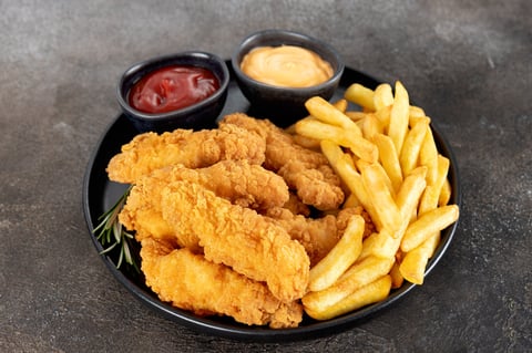Crispy chicken breast strips with ketchup on a dark background