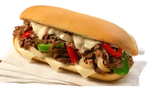 Cheesesteak sandwich with sautéed mushrooms, peppers, and melted cheese on a toasted roll