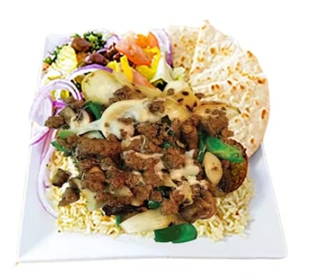 Plated Asian noodle dish with beef, vegetables, and edible flowers garnish on white square plate