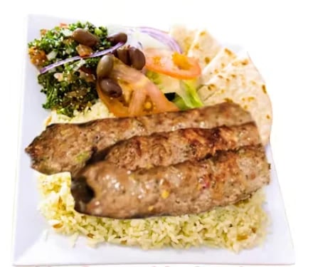 Grilled meat kebabs served on herb rice with fresh salad, olives, and flatbread on a white plate